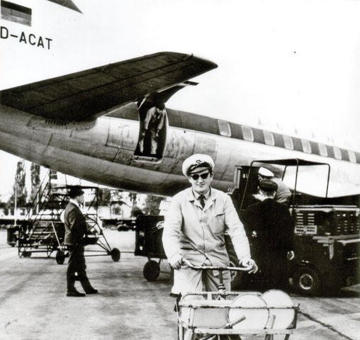 Ein Einweiser fährt mit einem Fahrrad von einem Flugzeug weg, das gerade beladen wird.