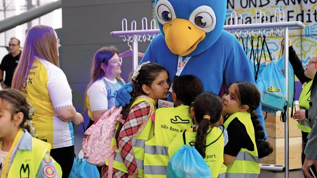Kinder feiern am Airport den Weltkindertag mit einem Maskottchen