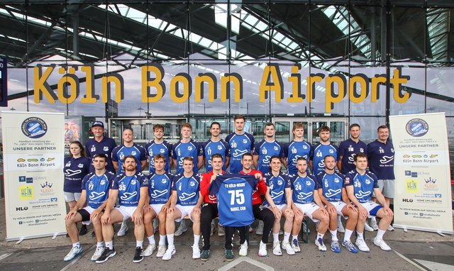 Handballmannschaft mit den vom Flughafen gesponserten Trikots vor dem Terminal 2.
