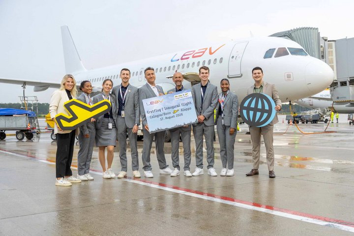 Das CGN Airline Marketing feiert mit der LEAV Crew den Erstflug vor einem LEAV Flugzeug auf dem Vorfeld.