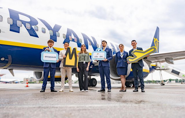 Mitarbeiter des Flughafens feiern den Erstflug mit der Ryanair Crew vor einem Flugzeug auf dem Vorfeld.